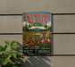 A vintage-style metal sign advertising cranberry glades, a botanical area, with a scenic landscape featuring a lake, pine trees, and wildflowers.