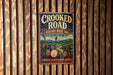 A vintage metal sign with the text "Crooked Road" and "Heritage Music Trail Virginia" displayed on a wooden wall.