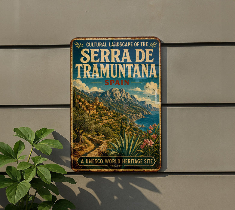 A vintage-style metal sign with the text "CULTURAL LANDSCAPE OF SERRA DE TRAMUNTANA SPAN" and "A UNESCO WORLD HERITAGE SITE" is displayed on a wall, with a plant to the left.
