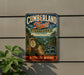 A vintage metal sign for the Cumberland Trail in Tennessee, featuring a scenic mountain landscape and a trail marker.