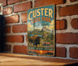 A vintage metal sign for Custer State Park in South Dakota, featuring a buffalo and a scenic landscape.