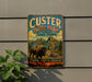 A vintage metal sign for Custer State Park in South Dakota, featuring a buffalo and a red car in a scenic landscape.