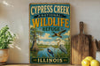 a vintage-style sign for the Cypress Creek National Wildlife Refuge in Illinois, with illustrations of birds and a natural landscape.