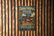 A vintage-style metal sign for the Dana Thomas House in Illinois, featuring an illustration of the building and the text "Dana Thomas House Frank Lloyd Wright Masterpiece Springfield Illinois".