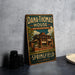 A vintage-style metal sign for the Dana Thomas House in Springfield, Illinois, featuring an illustration of the house and the text "Dana Thomas House Frank Lloyd Wright Masterpiece" and "Springfield Illinois".