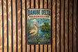 A vintage metal sign with the text "DANUBE DELTA ROMANIA" and an illustration of a pelican standing in a pond surrounded by tall grass and trees.