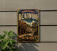 A vintage metal sign for Deadwood, South Dakota, featuring an old-fashioned saloon and a horse-drawn carriage, mounted on a wall.