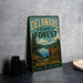 A vintage metal sign for Delaware State Forest, featuring a scenic landscape with pine trees, a lake, and mountains.