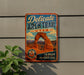 A vintage-style metal sign advertising the Delicate Arch Trail in Utah, featuring an illustration of the iconic rock formation.