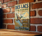 A vintage-style sign for the Des Lacs National Wildlife Refuge in North Dakota, featuring a duck in flight and text promoting wildlife preservation and conservation.