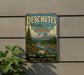 A vintage-style metal sign advertising Deschutes National Forest in Oregon, featuring a scenic mountain landscape and a river.