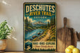 A vintage-style metal sign advertising the Deschutes River Trail in Oregon, featuring a scenic mountain landscape with a river and forest.
