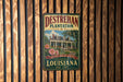 A vintage-style metal sign for the Destrehan Plantation in Louisiana, featuring a house and palm trees, mounted on a wooden wall.