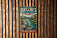 A vintage-style metal sign for Devil's River, a state natural area in Texas, is displayed on a wooden wall.