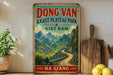 A vintage-style sign for "Dong Van Karst Plateau Park" in Vietnam, featuring a scenic mountain landscape with a winding road.