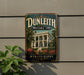 A vintage sign for Dunleith Historic Inn in Mississippi, featuring a large image of a historic building surrounded by trees and flowers.