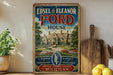 A vintage-style sign for Edsel & Eleanor Ford House, featuring a large illustration of the house and the Ford logo, is displayed on a shelf next to a wooden cutting board and some lemons.