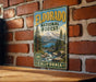 A vintage-style metal sign for Eldorado National Forest in California, featuring a scenic landscape with mountains, pine trees, and a river.