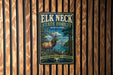 A metal sign with a vintage-style illustration of a deer in a forest, mounted on a wooden wall.