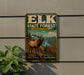 A metal sign with a picture of a deer in a forest, mounted on a wall.