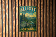 A vintage metal sign for Elliott State Forest in Oregon, featuring a scenic landscape with pine trees and mountains.