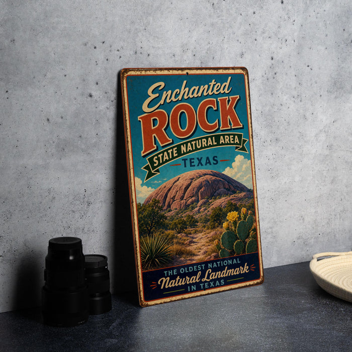 A vintage-style sign for the Enchanted Rock State Natural Area in Texas, featuring a desert landscape with a large rock formation and cacti.