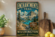 A vintage-style metal sign for the Enchanted Trail in Washington, featuring a scenic mountain landscape with a lake and pine trees.