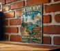 A vintage metal sign for the Enchanted Trail in Washington, featuring a mountain landscape and a trail sign.