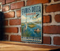 A vintage metal sign with the text "EVROS DELTA GREECE" and an illustration of a seagull, a lighthouse, and a boat on a body of water.