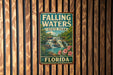 A vintage-style sign for Falling Waters State Park in Florida, featuring a waterfall and tropical foliage.