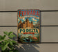 A vintage-style metal sign with the text "FERRARA CITY OF THE RENAISSANCE AND ITS PO DELTA ITALY" and an illustration of a cityscape with a castle, birds, and a river.