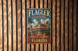 A vintage metal sign for the Flagler Museum in Florida, featuring an illustration of a historic hotel with palm trees and a blue sky.