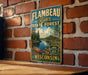 A vintage-style metal sign for the Flamebeau River State Forest in Wisconsin, featuring a scenic illustration of a lake, forest, and canoe.