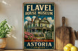 A vintage-style metal sign for the Fl aval House Museum in Astoria, Oregon, featuring an illustration of a Victorian-style house surrounded by flowers and greenery.