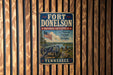 A vintage metal sign for Fort Donelson National Battlefield in Tennessee, featuring an American flag and a cannon, mounted on a wooden wall.