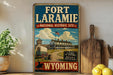 A vintage-style sign for the Fort Laramie National Historic Site in Wyoming, featuring an illustration of a wagon train and a large white house.