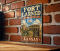 A vintage-style metal sign for the Fort Larned National Historic Site in Kansas, featuring an illustration of a historical building and cannon.