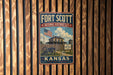 A vintage-style metal sign for the Fort Scott National Historic Site in Kansas, featuring an American flag and a building with a wooden fence.