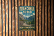 A vintage metal sign for Franconia Notch State Park in New Hampshire, featuring a scenic mountain landscape.
