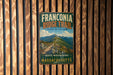 A vintage metal sign for the Franconia Ridge Trail in Massachusetts, featuring a scenic mountain landscape.