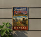 A vintage-style metal sign advertising the "Frontier National Heritage Area" in Kansas, featuring an illustration of a covered wagon and a steamboat.