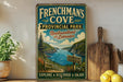 A vintage-style sign for "Frenchman's Cove Provincial Park" in Newfoundland and Labrador, featuring a scenic landscape with a lake and mountains.