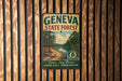 A vintage metal sign for the Geneva State Forest, featuring a scenic image of a forest and a lake, mounted on a wooden wall.