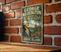 A vintage metal sign with a portrait of George Washington, the first President of the United States, and the text "GEORGE WASHINGTON MEMORIAL STATE FOREST RHODE ISLAND".