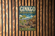 A vintage-style metal sign for the Ginkgo Petrified Forest State Park in Washington, featuring a scenic landscape with a ginkgo tree and log cabins.