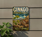 A vintage-style metal sign for Ginkgo Petrified Forest State Park in Washington, featuring a scenic landscape with a ginkgo tree and a clock.