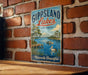 A vintage-style metal sign with the text "Gippsland Lakes" and "Australia" is displayed on a brick wall.