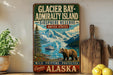 A vintage-style sign for Glacier Bay-Admiralty Island, featuring a scenic image of a bear and a boat on a lake surrounded by mountains.