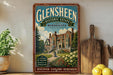 a vintage-style sign for Glensheen Historic Estate in Minnesota, with a large illustration of a historic building surrounded by a well-manicured garden. The sign is displayed on a shelf next to a wooden cutting board and a potted plant, creating a rustic and charming atmosphere.