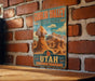 A vintage-style metal sign for Goblin Valley State Park, featuring a desert landscape with rock formations and mountains.